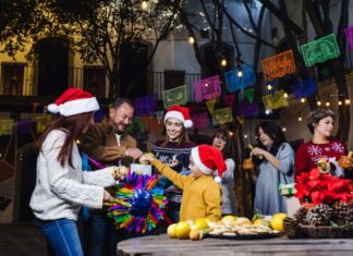 ¿Cuándo comienza y cuándo termina la Navidad? Familia y amigos reunidos en una posada navideña, rompiendo una piñata, con luces cálidas y ambiente de convivencia, paz y alegría.