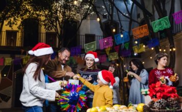 ¿Cuándo comienza y cuándo termina la Navidad? Familia y amigos reunidos en una posada navideña, rompiendo una piñata, con luces cálidas y ambiente de convivencia, paz y alegría.