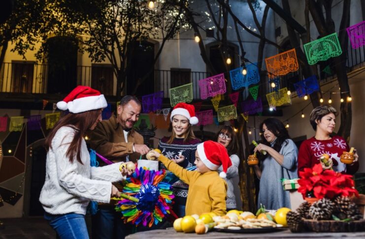 ¿Cuándo comienza y cuándo termina la Navidad? Familia y amigos reunidos en una posada navideña, rompiendo una piñata, con luces cálidas y ambiente de convivencia, paz y alegría.