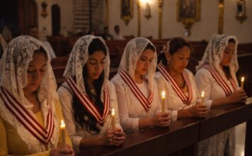 La Iglesia que vela cuando el mundo duerme Grupo de mujeres mexicanas en una iglesia, con velo blanco y velas encendidas, orando en silencio durante una vigilia de adoración eucarística nocturna.