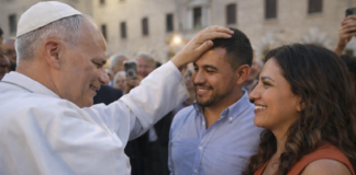 León XIV convoca a los obispos del mundo: algo está pasando con la familia… y la Iglesia lo sabe El Papa León XIV coloca su mano sobre la cabeza de un hombre latino mientras conversa con él y su pareja en una plaza, en un gesto cercano y pastoral.