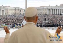 León XIV explica qué es la Iglesia y por qué no se puede vivir la fe en solitario El Papa León XIV, visto de espaldas, levanta las manos mientras se dirige a una multitud reunida en la Plaza de San Pedro en el Vaticano.