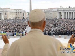 León XIV explica qué es la Iglesia y por qué no se puede vivir la fe en solitario El Papa León XIV, visto de espaldas, levanta las manos mientras se dirige a una multitud reunida en la Plaza de San Pedro en el Vaticano.