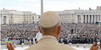 León XIV explica qué es la Iglesia y por qué no se puede vivir la fe en solitario El Papa León XIV, visto de espaldas, levanta las manos mientras se dirige a una multitud reunida en la Plaza de San Pedro en el Vaticano.