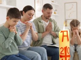 Domingo de Resurrección: el dia que la vida vence y la alegría se comparte Familia reunida en casa en actitud de oración, con un cirio pascual encendido en primer plano, símbolo de la Resurrección de Cristo.