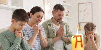 Domingo de Resurrección: el dia que la vida vence y la alegría se comparte Familia reunida en casa en actitud de oración, con un cirio pascual encendido en primer plano, símbolo de la Resurrección de Cristo.