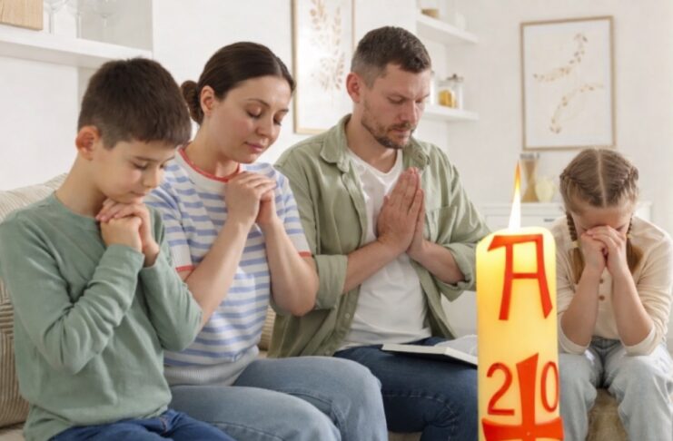 Domingo de Resurrección: el dia que la vida vence y la alegría se comparte Familia reunida en casa en actitud de oración, con un cirio pascual encendido en primer plano, símbolo de la Resurrección de Cristo.