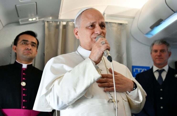 El Papa responde sin confrontar: “No soy un político… basta ya de guerras” El Papa León XIV hablando con un micrófono dentro de un avión, acompañado por miembros de su equipo, durante un encuentro con periodistas.