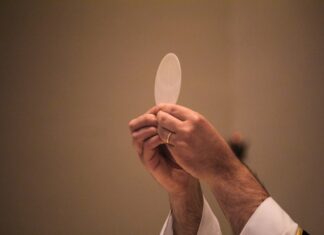 Corpus Christi: el Pan que nos da vida Sacerdote elevando una hostia consagrada durante la celebración de la Eucaristía, en un momento de adoración y recogimiento litúrgico.