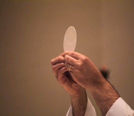Corpus Christi: el Pan que nos da vida Sacerdote elevando una hostia consagrada durante la celebración de la Eucaristía, en un momento de adoración y recogimiento litúrgico.