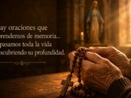 ¿Por qué rezamos el Ave María? Manos sostienen un rosario de madera dentro de una iglesia iluminada por la luz que entra por un vitral, mientras una imagen desenfocada de la Virgen María aparece al fondo.