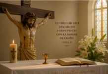 Julio y la Preciosísima Sangre de Cristo: una devoción que nos recuerda hasta dónde llega el amor de Dios Crucifijo sobre un altar con una Biblia abierta, un pequeño cáliz, un cirio encendido y lirios blancos, como representación de la devoción a la Preciosísima Sangre de Cristo durante el mes de julio.