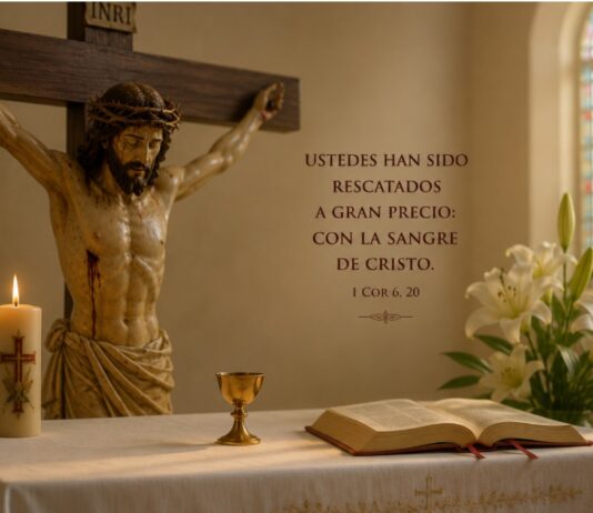 Julio y la Preciosísima Sangre de Cristo: una devoción que nos recuerda hasta dónde llega el amor de Dios Crucifijo sobre un altar con una Biblia abierta, un pequeño cáliz, un cirio encendido y lirios blancos, como representación de la devoción a la Preciosísima Sangre de Cristo durante el mes de julio.