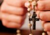 Rezar el Rosario por los difuntos: una oración de esperanza y amor Persona sosteniendo un rosario mientras ora por el eterno descanso de los fieles difuntos.