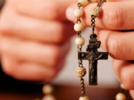 Rezar el Rosario por los difuntos: una oración de esperanza y amor Persona sosteniendo un rosario mientras ora por el eterno descanso de los fieles difuntos.